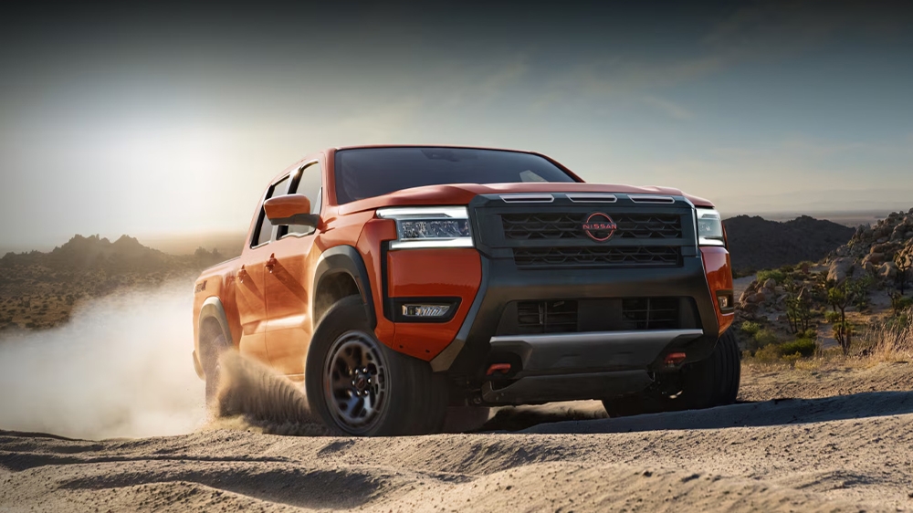 Vue avant du Nissan Frontier en puissance dans un chemin de sable