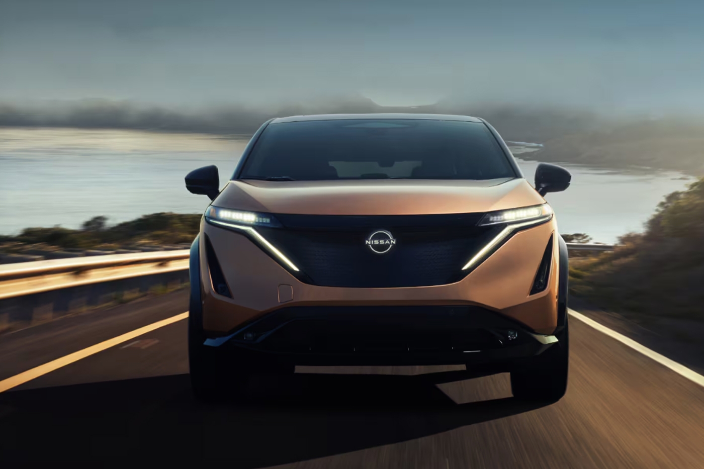 Vue avant du Nissan Ariya 2026 sur route avec vue sur mer